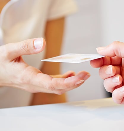 Close-up of a person handing over a card to another person.